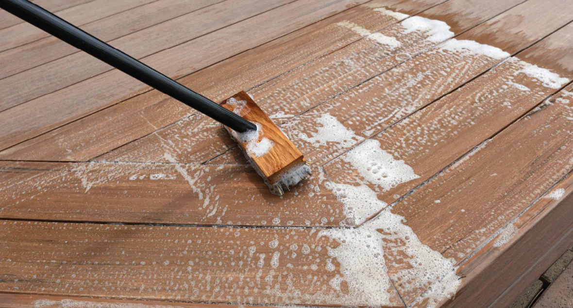 Cleaning a wooden deck with a soapy brush for maintenance and care.
