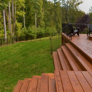 a wooden deck with railings and grass and trees