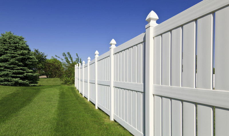a white fence with grass and trees with Nelson-Atkins Museum of Art in the background