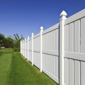 a white fence with grass and trees with Nelson-Atkins Museum of Art in the background